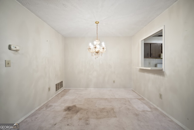 unfurnished room with a textured ceiling, light colored carpet, and a notable chandelier