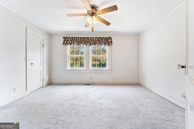 spare room featuring ceiling fan, ornamental molding, a textured ceiling, and light carpet