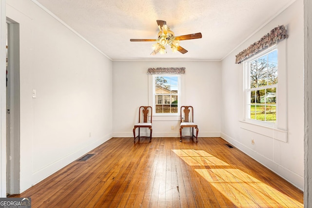 unfurnished room featuring a wealth of natural light, a textured ceiling, and hardwood / wood-style flooring