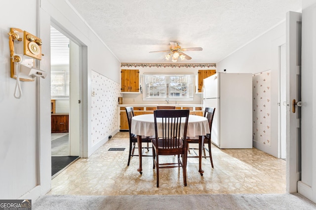 dining space featuring ceiling fan, crown molding, a textured ceiling, and sink