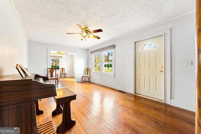 foyer entrance featuring a textured ceiling, light hardwood / wood-style floors, ceiling fan, and ornamental molding