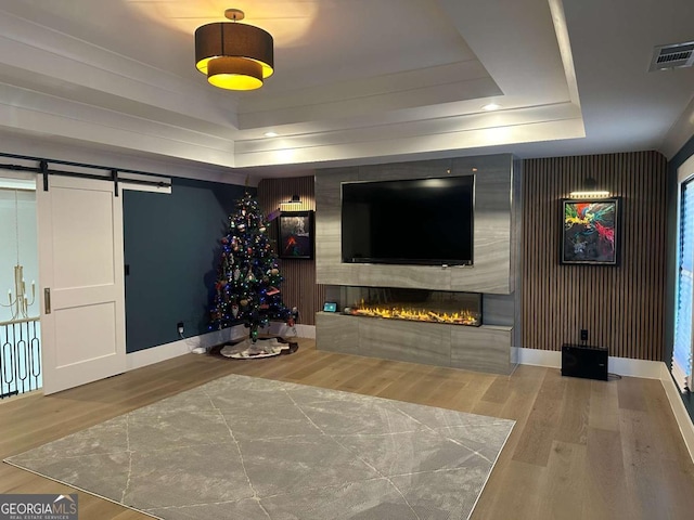 living room featuring hardwood / wood-style floors, a barn door, and a raised ceiling