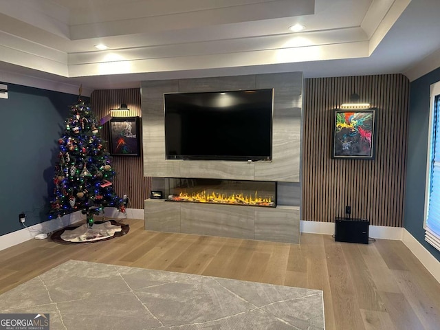 unfurnished living room featuring a large fireplace, hardwood / wood-style flooring, and a raised ceiling