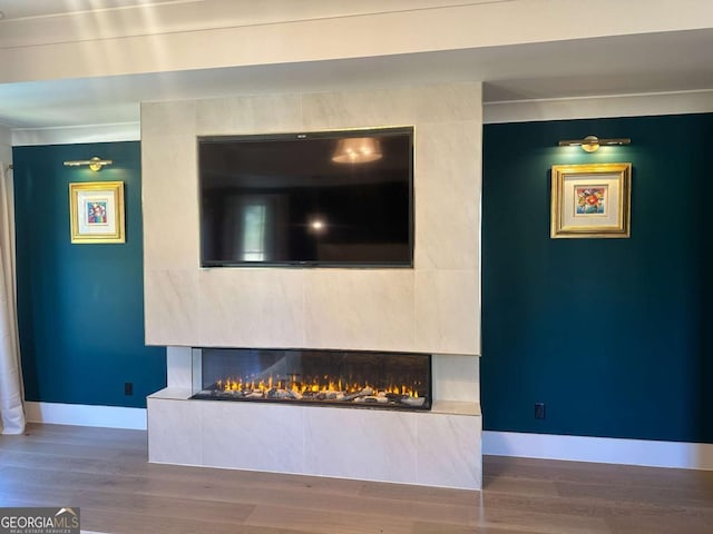 unfurnished living room featuring a tile fireplace, crown molding, and hardwood / wood-style floors