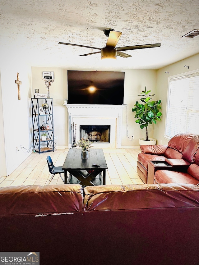 living room featuring ceiling fan, a textured ceiling, and hardwood / wood-style flooring