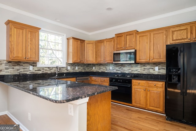 kitchen with dark stone counters, kitchen peninsula, light hardwood / wood-style flooring, and black appliances