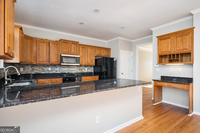 kitchen featuring black refrigerator, kitchen peninsula, dark stone counters, and sink