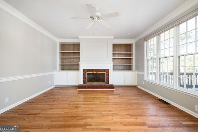 unfurnished living room featuring ceiling fan, light wood-type flooring, crown molding, and a brick fireplace