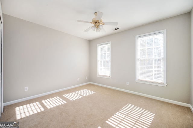 empty room with light colored carpet, plenty of natural light, and ceiling fan