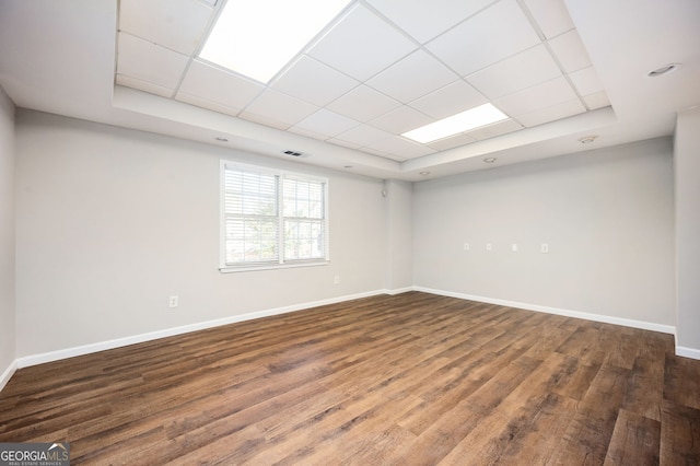 unfurnished room featuring a raised ceiling, a drop ceiling, and dark wood-type flooring