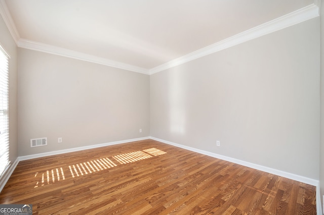 empty room featuring wood-type flooring, plenty of natural light, and ornamental molding