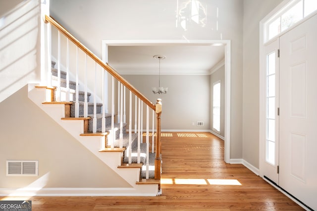 foyer entrance featuring crown molding, a chandelier, and hardwood / wood-style flooring