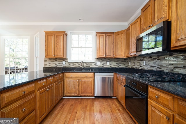 kitchen with black appliances, light wood-type flooring, sink, and dark stone counters