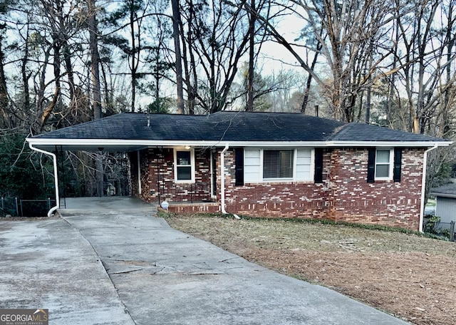 ranch-style house with a carport, driveway, brick siding, and a shingled roof