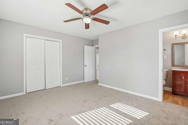 unfurnished bedroom featuring carpet floors, a closet, a sink, and baseboards