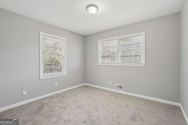 carpeted spare room featuring baseboards, visible vents, and a healthy amount of sunlight