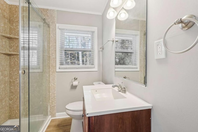 bathroom featuring a stall shower, toilet, wood finished floors, crown molding, and vanity