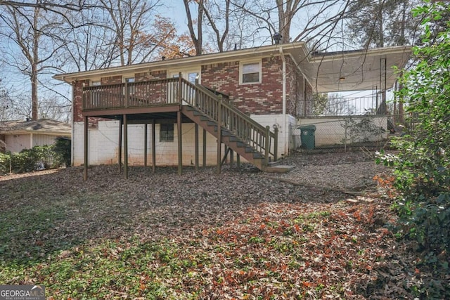 rear view of house with an attached garage, a wooden deck, stairs, and brick siding