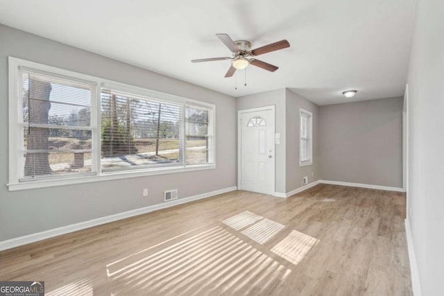 interior space featuring a ceiling fan, wood finished floors, visible vents, and baseboards