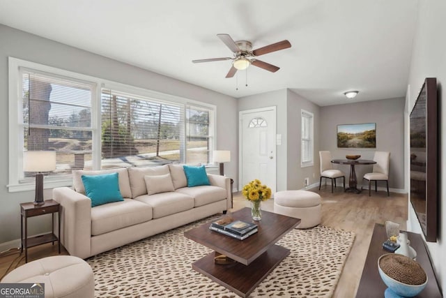 living area featuring a ceiling fan, baseboards, and wood finished floors