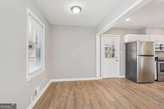 kitchen with light wood finished floors, visible vents, white cabinets, baseboards, and stainless steel appliances