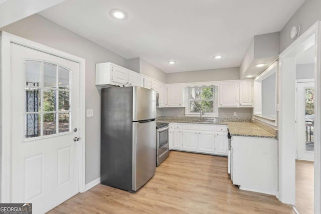 kitchen with stainless steel appliances, light wood finished floors, light stone countertops, and white cabinets