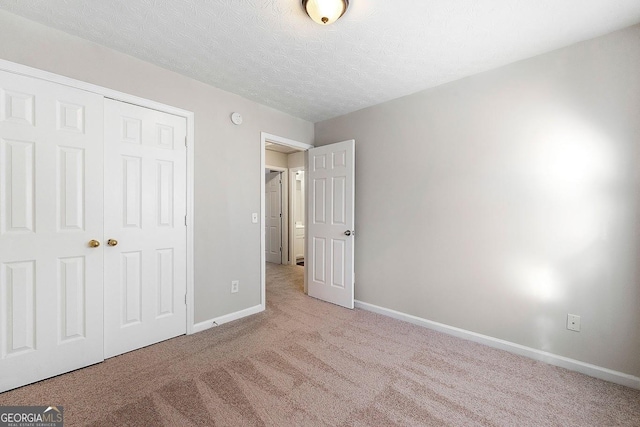 unfurnished bedroom featuring a closet, light colored carpet, and a textured ceiling