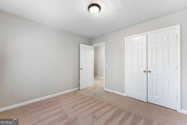 unfurnished bedroom featuring light carpet, a textured ceiling, and a closet