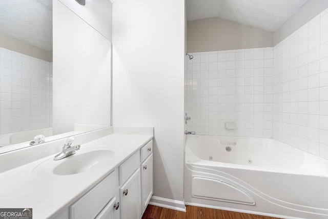 bathroom featuring shower / bath combination, vaulted ceiling, wood-type flooring, a textured ceiling, and vanity