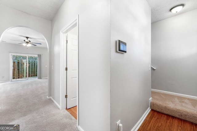 hallway with light colored carpet and a textured ceiling