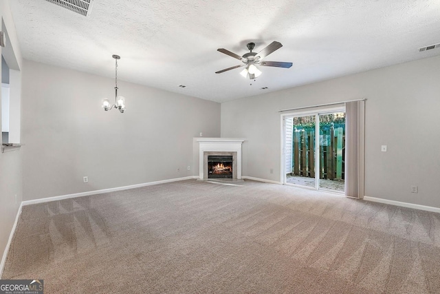 unfurnished living room featuring ceiling fan with notable chandelier, carpet, and a textured ceiling