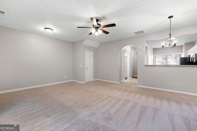 carpeted spare room with a textured ceiling, ceiling fan with notable chandelier, and vaulted ceiling