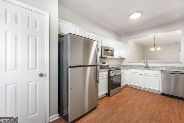 kitchen featuring white cabinets, pendant lighting, and stainless steel appliances