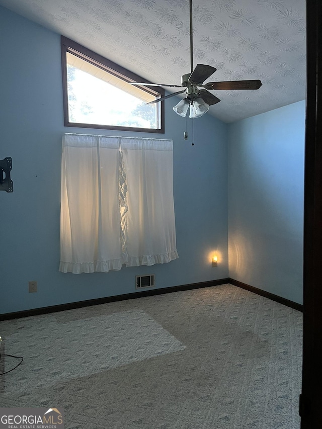 unfurnished room with carpet floors, lofted ceiling, visible vents, a textured ceiling, and baseboards