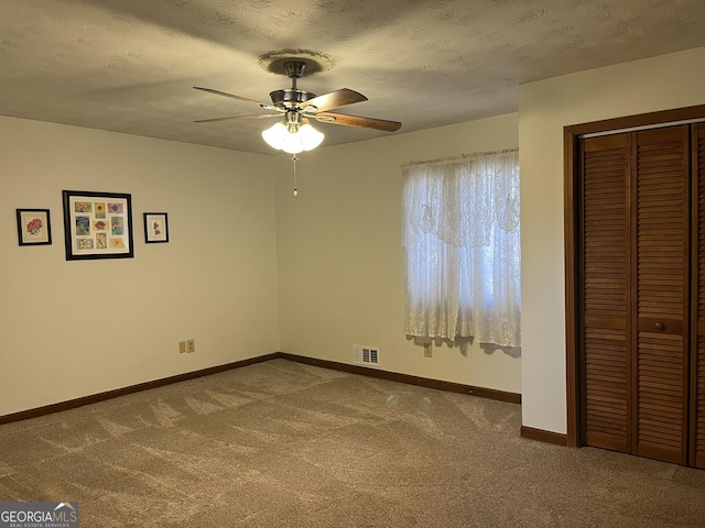 unfurnished bedroom featuring visible vents, baseboards, a closet, a textured ceiling, and carpet flooring