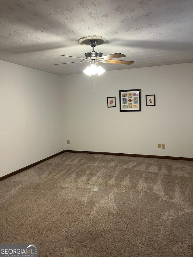 carpeted spare room with a textured ceiling, ceiling fan, and baseboards