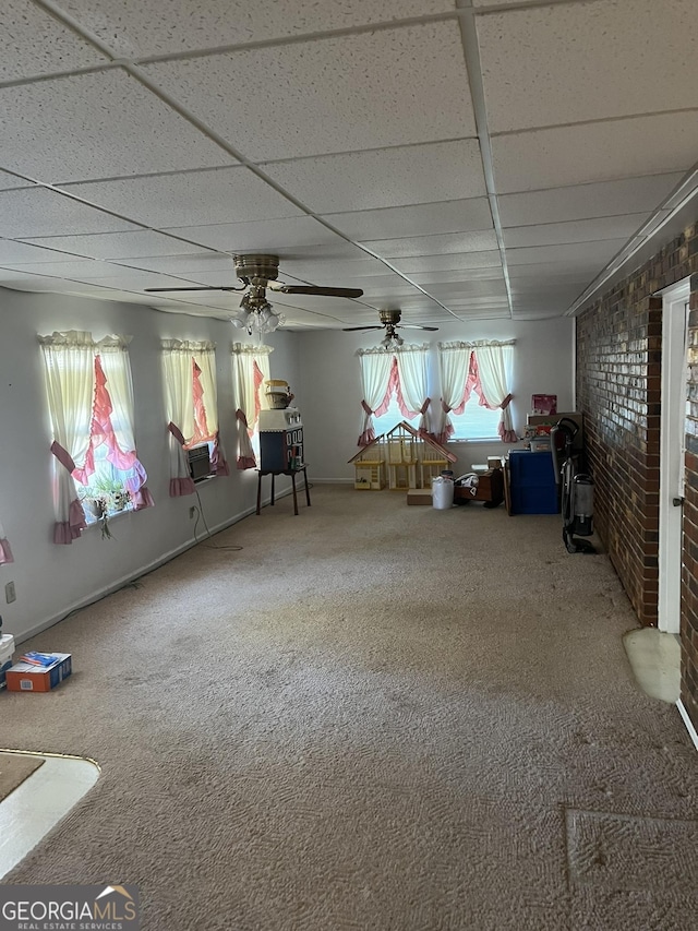 interior space with carpet, ceiling fan, brick wall, cooling unit, and a drop ceiling