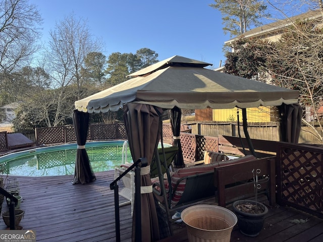 deck with fence, a fenced in pool, and a gazebo