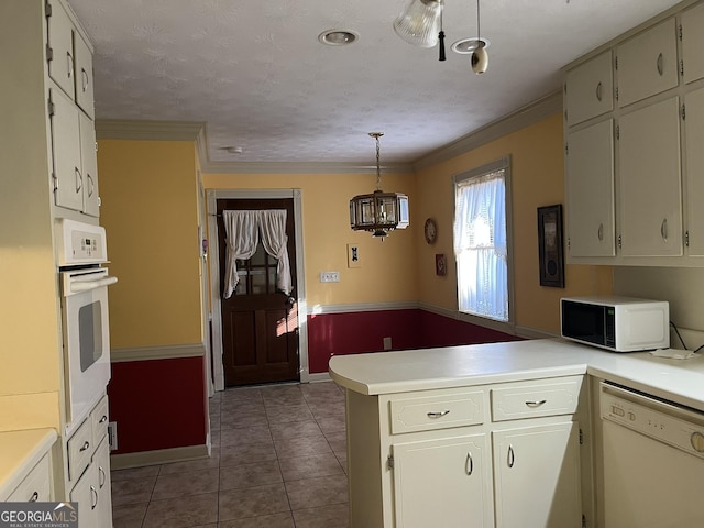 kitchen with a peninsula, white appliances, light countertops, tile patterned floors, and pendant lighting