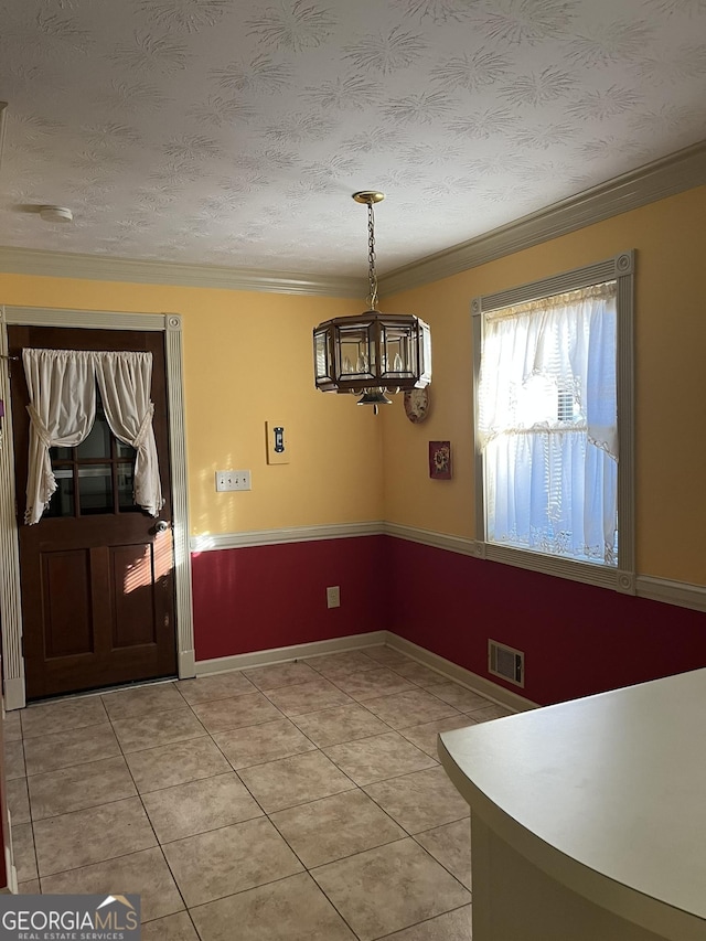 unfurnished dining area with visible vents, crown molding, a textured ceiling, and an inviting chandelier