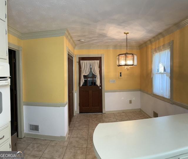 kitchen with a notable chandelier, ornamental molding, light tile patterned floors, white cabinets, and visible vents