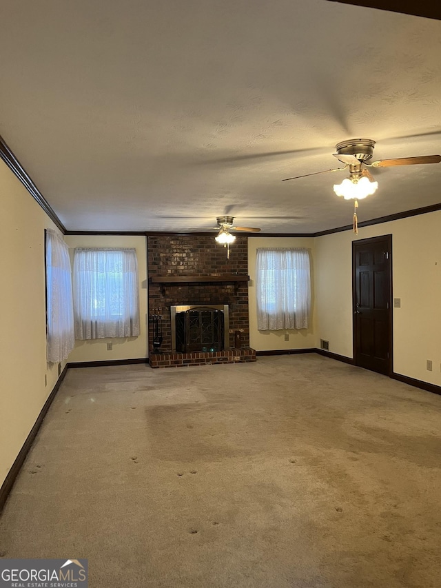 unfurnished living room with a ceiling fan, a fireplace, ornamental molding, and carpet flooring