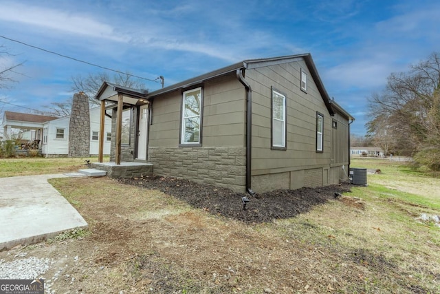 view of side of property with central air condition unit and a yard