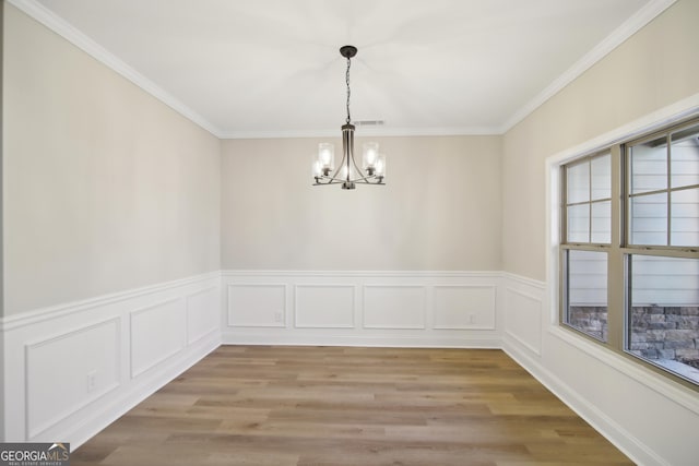 unfurnished dining area with light hardwood / wood-style flooring, ornamental molding, and an inviting chandelier