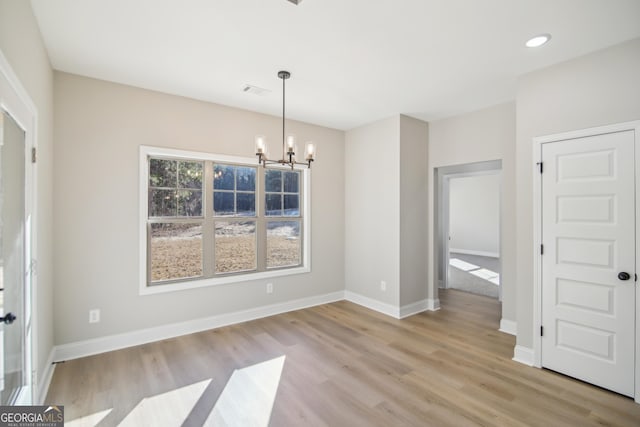 unfurnished dining area with light hardwood / wood-style flooring and a notable chandelier