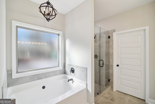 bathroom featuring tile patterned flooring, shower with separate bathtub, and an inviting chandelier