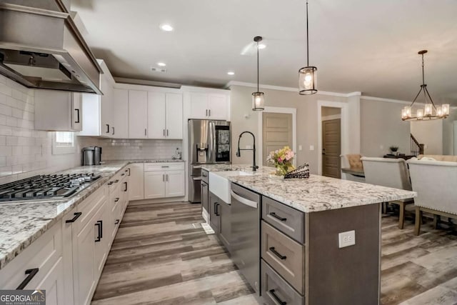 kitchen featuring pendant lighting, stainless steel appliances, white cabinetry, and a kitchen island with sink