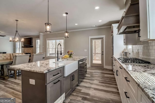 kitchen with white cabinets, pendant lighting, a center island with sink, and appliances with stainless steel finishes