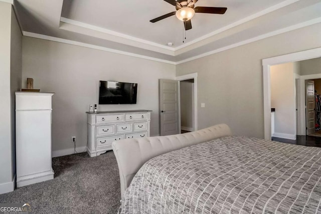 bedroom with a tray ceiling, dark carpet, and ceiling fan