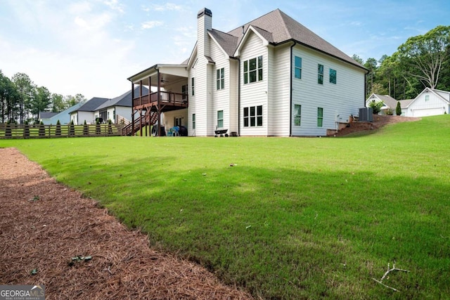 back of house featuring a lawn, a wooden deck, and central AC